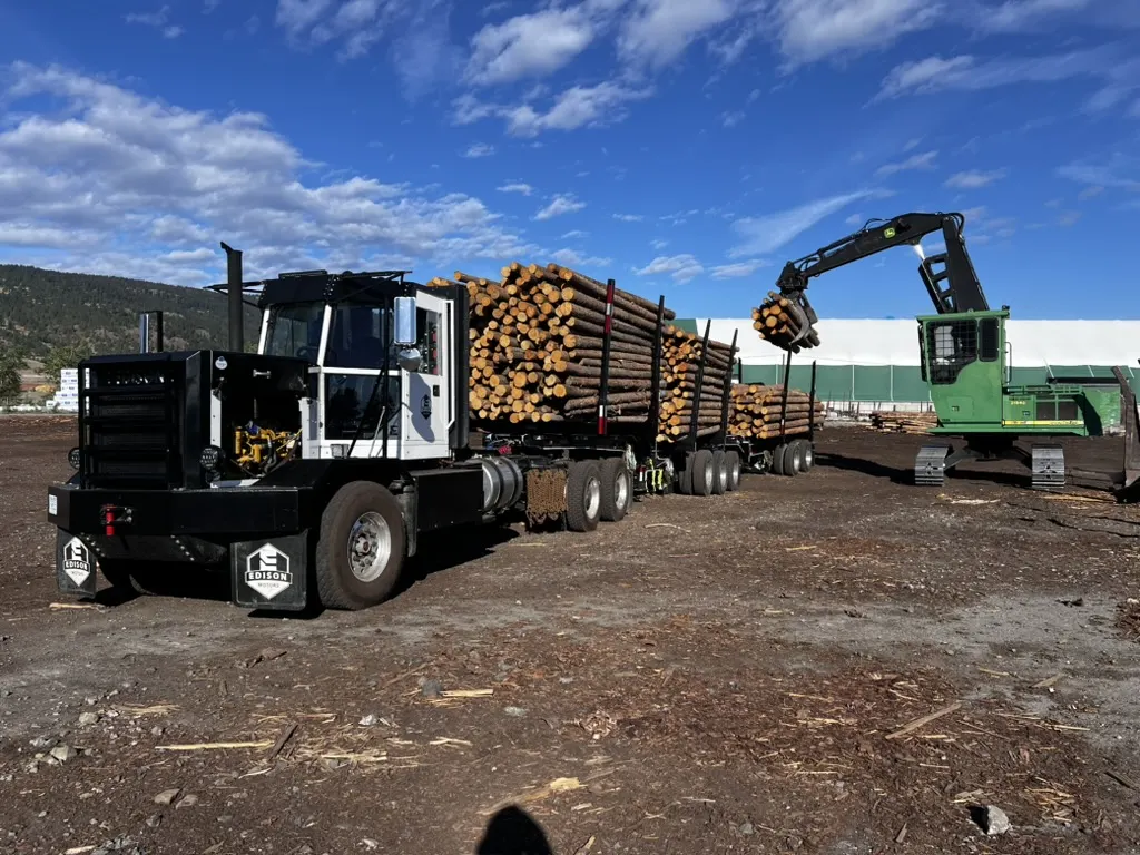 Edison Motors diesel-electric logging truck Topsy being loaded with logs by a log loader
